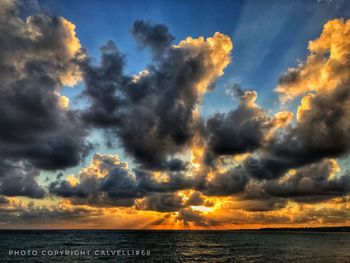 Scenic view of sea against dramatic sky during sunset