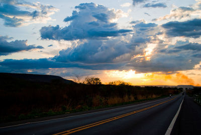 Country road against sky during sunset