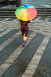 Rear view of woman with umbrella walking on street