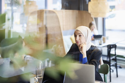 Woman in headscarf sitting in cafe