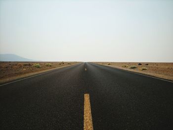 Diminishing perspective of empty road against clear sky
