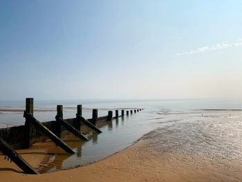 Wooden posts on beach against sky