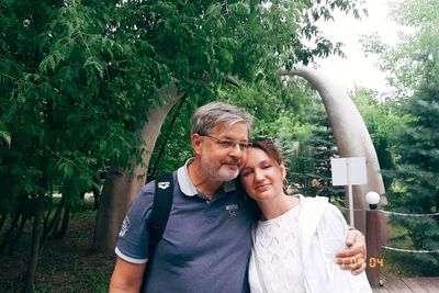 Portrait of happy man and woman against trees