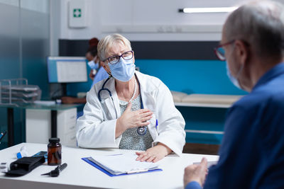 Doctor wearing mask consulting patient at clinic