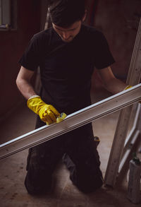 Young handsome caucasian brunette man is washing window frames with a sponge and soap