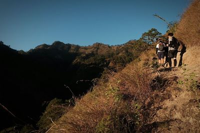 Hikers on mountain against clear sky