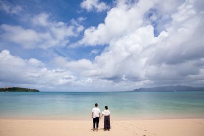 Rear view of couple on beach against sky