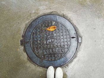 Low section of person standing on manhole