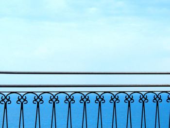 Low angle view of railing against blue sky
