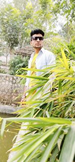 Portrait of young man standing by plants