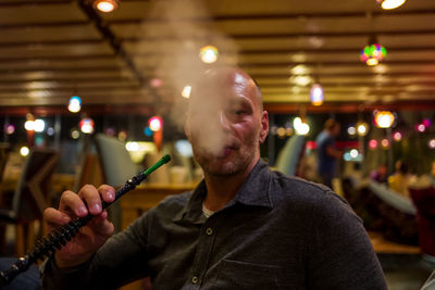 Portrait of man smoking hookah in bar