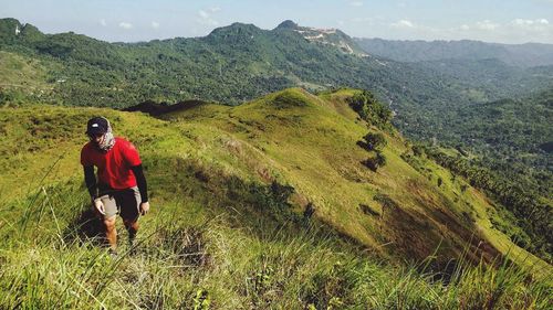 Rear view of man walking on mountain against sky