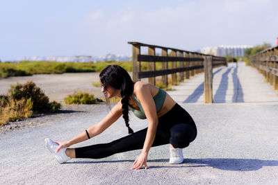 Woman stretching leg on road 