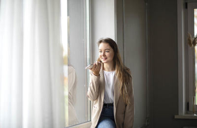 Work-life-balance, businesswoman on windowsill in the hall of office with smartphone. voice message