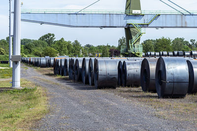 Metal sheets wrapped in large rolls, standing on the loading yard next to the railway tracks