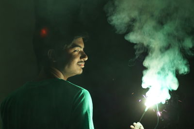 Rear view of man holding sparkler during night