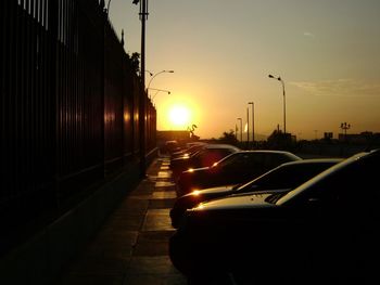 Cars at parking lot against sky during sunset