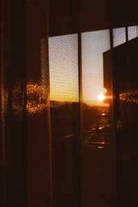 Illuminated building seen through glass window during sunset