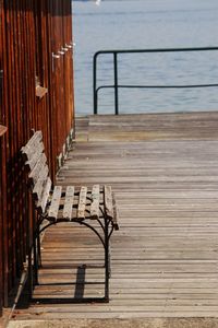Empty chairs and pier on sea