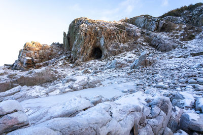 Rocks in frozen lake against sky during winter