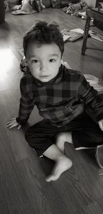 Portrait of cute boy sitting on hardwood floor at home