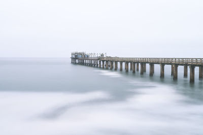 Pier over sea against clear sky