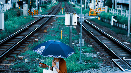 High angle view of woman with umbrella walking by railroad tracks