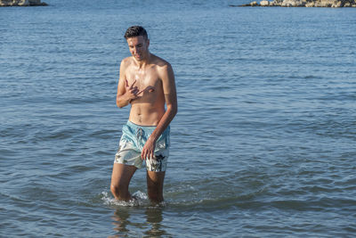 Shirtless man standing in sea