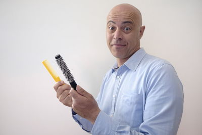 Portrait of smiling bald man holding comb