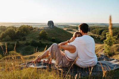 Man and woman enjoying picnic with beautiful sunset outdoors, scenic landscape