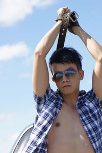 Low angle view of man standing with arms raised against sky