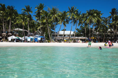 People swimming in pool by sea against clear sky