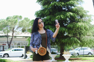 Young happy business woman relaxing in city, park. using phone. selfie. technology. summer vacation