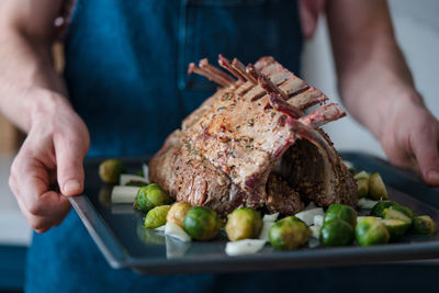 Roasted rack of lamb on a tray in the hands of the chef. barbecue season