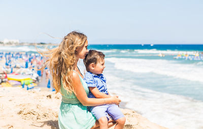 Mother and son sitting on beach