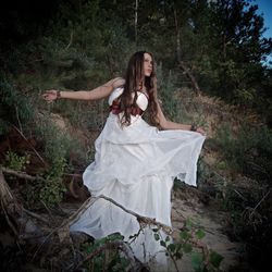 Young woman wearing white dress while standing in forest