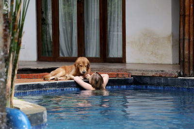 Rear view of woman swimming in pool by dog