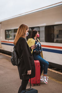 Woman standing by train at railroad station