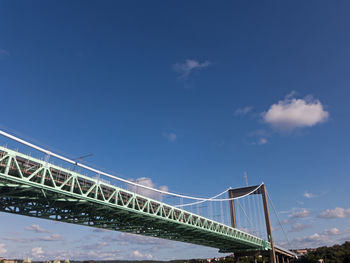 Low angle view of suspension bridge against blue sky