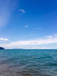 Person swimming in sea against blue sky