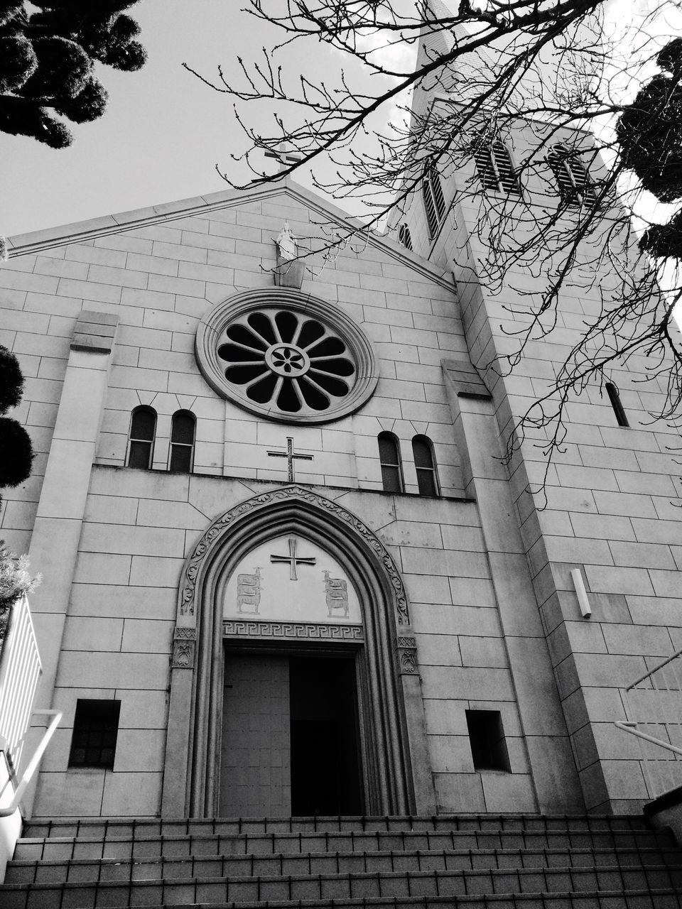 architecture, building exterior, built structure, low angle view, window, church, religion, facade, place of worship, building, arch, day, city, sky, outdoors, no people, spirituality, cross