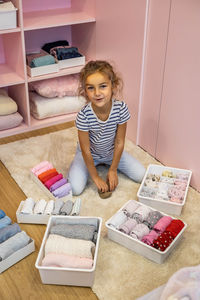Portrait of smiling girl sitting by towels in container at home