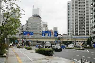 Cars on road by city against sky