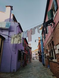 Clothes drying on alley amidst buildings against sky