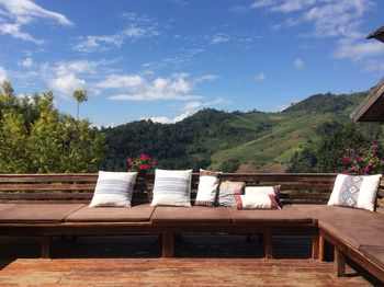 Chairs and table against trees and mountains against sky