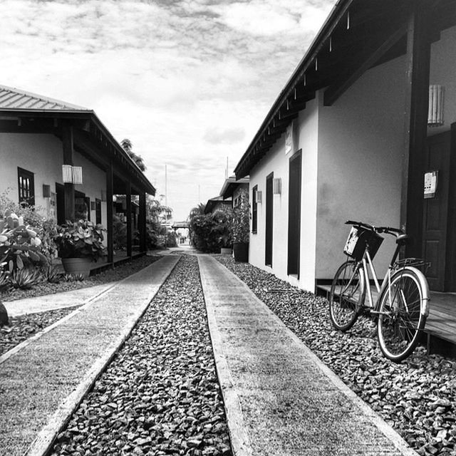 architecture, building exterior, built structure, transportation, the way forward, sky, diminishing perspective, vanishing point, residential structure, house, cobblestone, city, street, residential building, bicycle, cloud - sky, mode of transport, railroad track, day, long