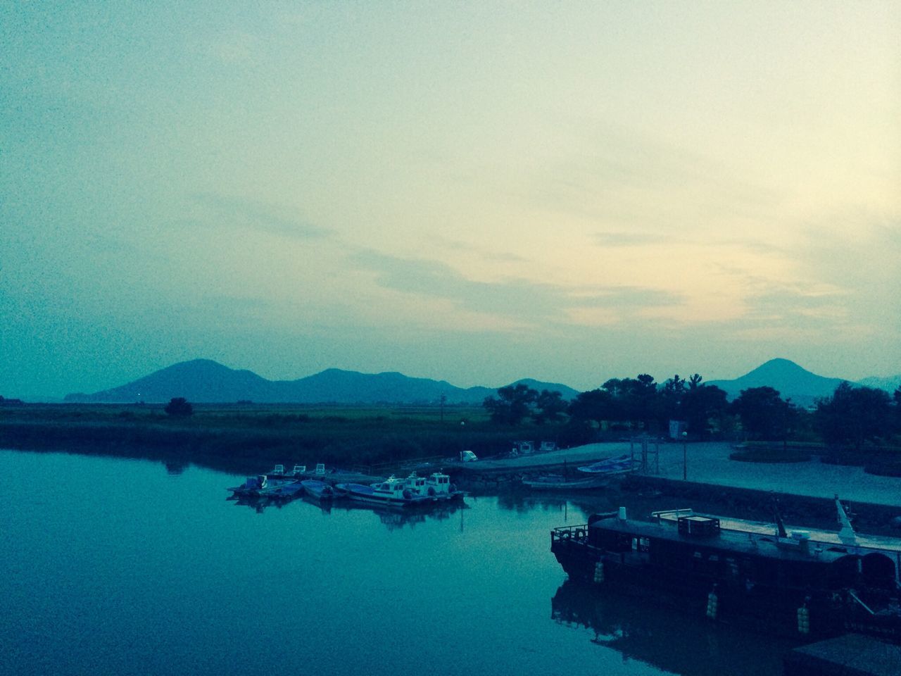 water, nautical vessel, moored, tranquility, lake, tranquil scene, reflection, sky, waterfront, boat, transportation, scenics, nature, beauty in nature, mode of transport, blue, calm, standing water, outdoors, mountain