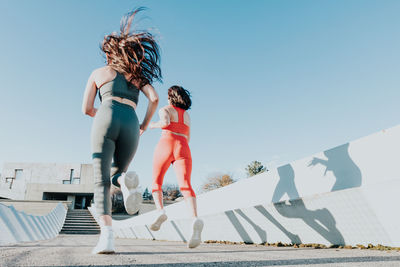 Rear view of woman running sky