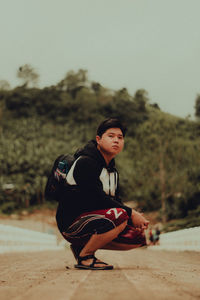 Full length of young man crouching on field