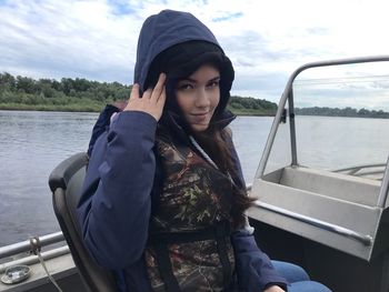 Portrait of young woman sitting on boat against sky